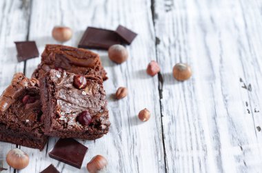 Beyaz, ahşap bir masa üzerinde çikolatalı şeker ve fındıklı ev yapımı browni. Bulanık arkaplan ile seçmeli odak.