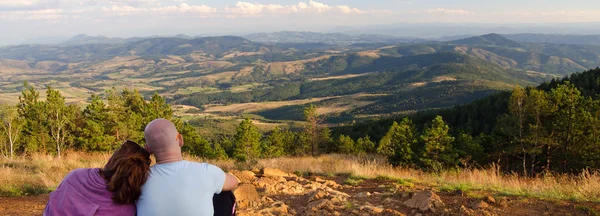 Pareja joven sentada en la cima de la montaña en verano soleado — Foto de Stock