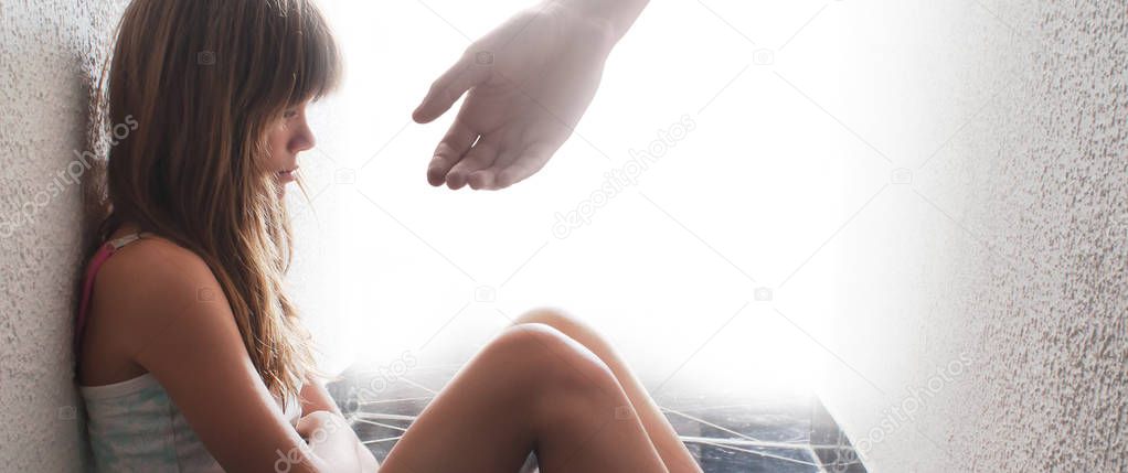Sad teenage girl sitting on the floor while hand is offering hep
