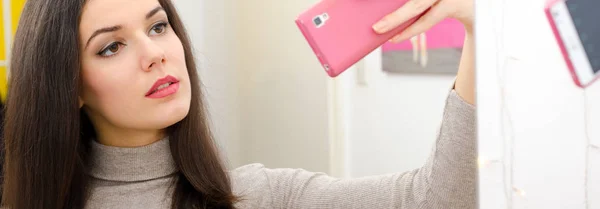 Beautiful girl with long black hair taking selfies in front of the mirror — Stock Photo, Image