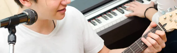 Menino adolescente tocando guitarra elétrica e cantando enquanto a menina joga — Fotografia de Stock