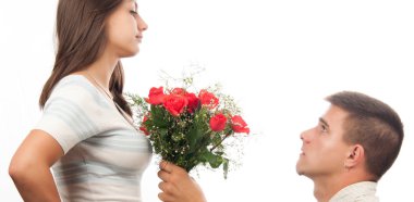 Young man kneeling and giving bouquet of roses to his girlfriend clipart
