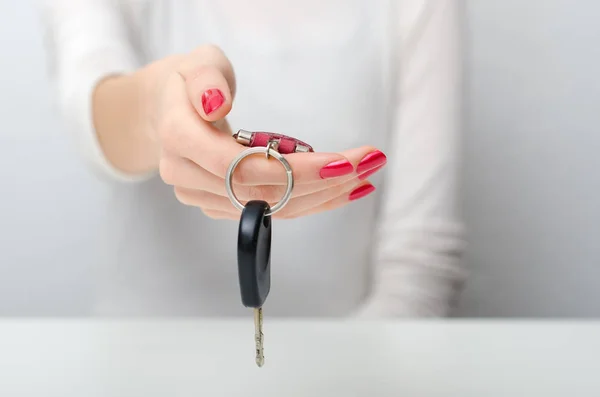 Female hand offering or giving car keys while sitting at white table