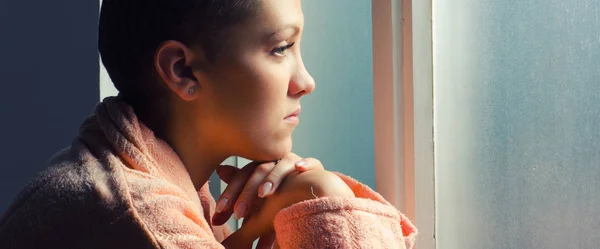Junge Krebspatientin steht vor Krankenhausfenster — Stockfoto