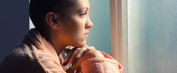 Young cancer patient standing in front of hospital window — Stock Photo, Image