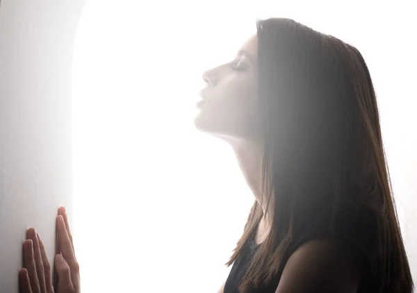 Portrait of the beautiful girl with closed eyes light shining on her face — Stock Photo, Image