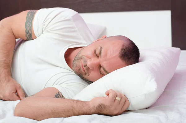Muskulöser junger Mann mit Tätowierungen am Arm, der friedlich schläft — Stockfoto