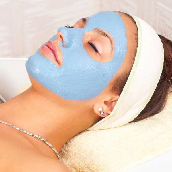Chica con máscara facial y los ojos cerrados acostado en el moderno spa de belleza —  Fotos de Stock