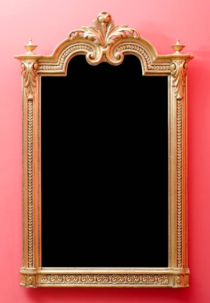 Prachtige antieke houten spiegel frame in gouden kleuren gemonteerd op de rode muur — Stockfoto