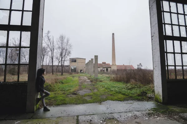 Hermosa joven gótica de pie a la entrada de abandonado — Foto de Stock