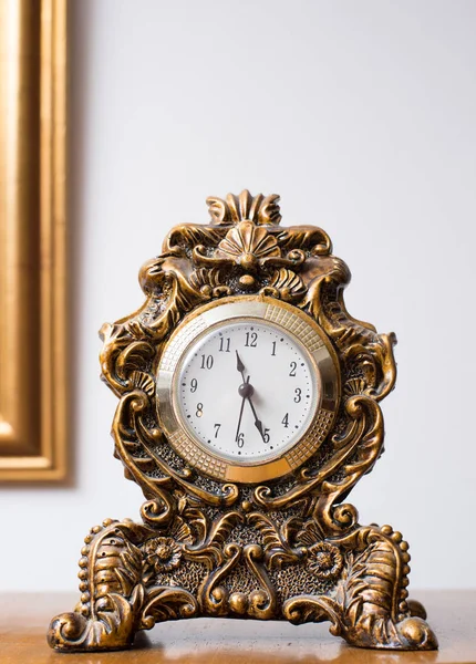 Antique clock in golden colors decorated with ornaments and reliefs