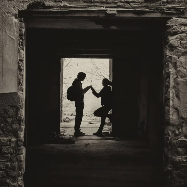 Silhouete di ragazzo e ragazza che si incontrano segretamente in un edificio abbandonato — Foto Stock