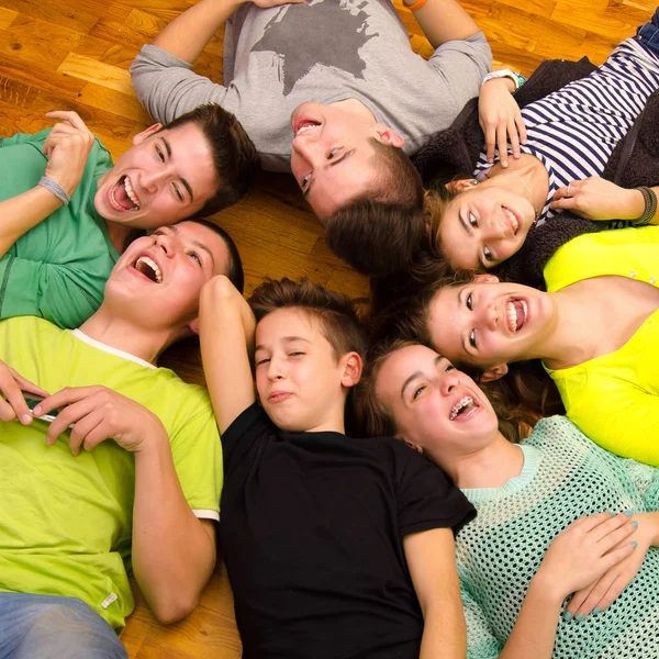 Teenage boys and girls lying on the floor, joking, laughing and having fun — Stock Photo, Image