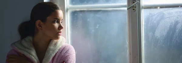 Beautiful ill sad cancer patient girl in pajamas  looking through hospital window — Stock Photo, Image
