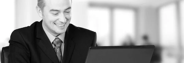 Joven hombre de negocios feliz trabajando en su oficina en blanco y negro — Foto de Stock