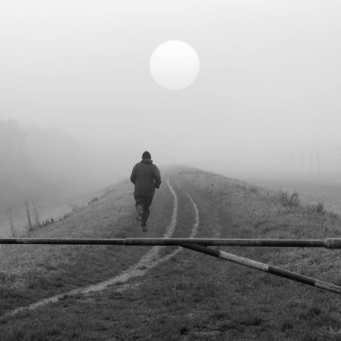 Genç adam doğada soğuk sisli sonbahar günü siyah beyaz koşu.
