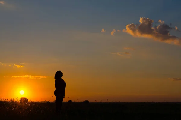 Silhouette of woman standing on the meadow during summer sunset — Stock Photo, Image