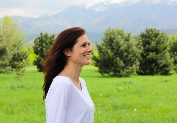 young woman in profile laughing in the mountains.