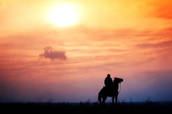 Jinete a caballo en una estepa durante el colorido atardecer, Kazakhsta — Foto de Stock