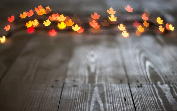 Autumn maple leaf bokeh on wooden background — Stock Photo, Image