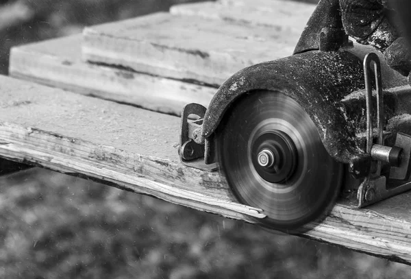Manos masculinas con sierra circular mientras se trabaja con madera en blanco y negro — Foto de Stock
