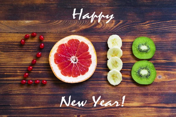 Feliz año nuevo 2018 de frutas y bayas sobre fondo de madera . — Foto de Stock