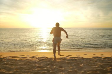 Sahilde denize günbatımında çalışan adam