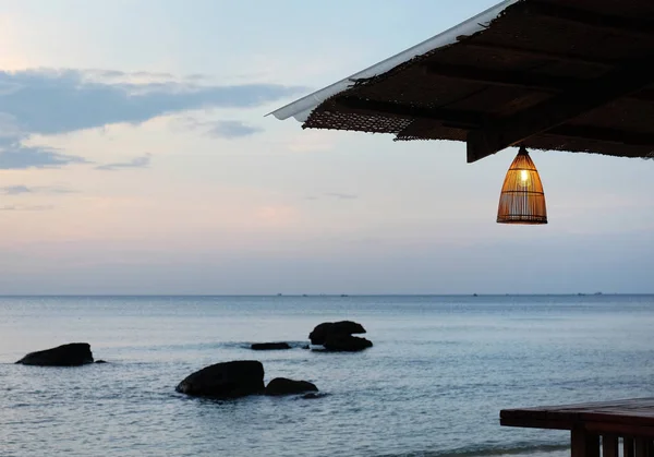 Acogedora cafetería con lámparas de bambú en la playa al atardecer . —  Fotos de Stock