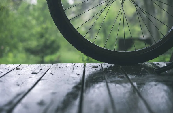 Bicycle wheel on the wooden floor under the rain — Stock Photo, Image