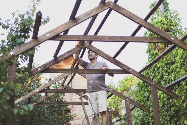Άνθρωπος κτίριο ξύλινη στέγη σε εξωτερικούς χώρους στέκεται στη σκάλα — Φωτογραφία Αρχείου