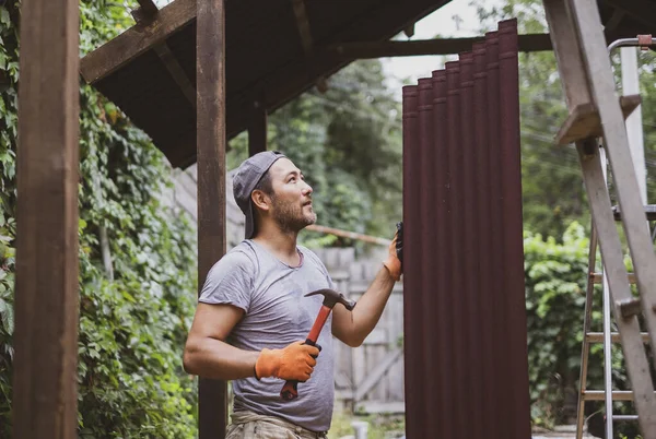 Homem edifício telhado e segurando martelo e material de telhado . — Fotografia de Stock