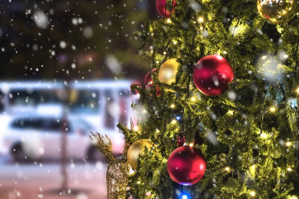 Christmas tree with lights glowing in city, snow falling. — Stock Photo, Image