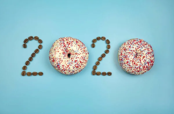 Nuevo año 2020 hecho de rosquillas y granos de café en el fondo azul —  Fotos de Stock