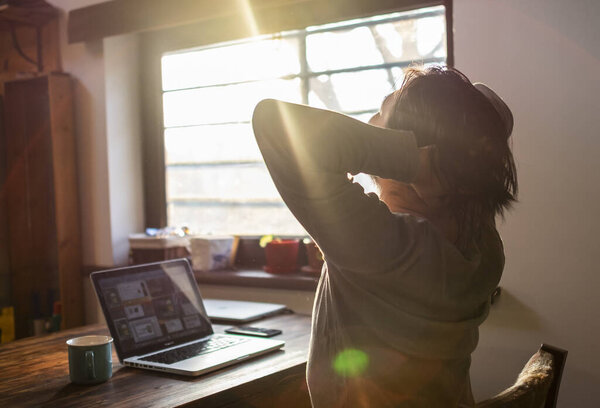 мужчина растягивается после работы на ноутбуке дома
