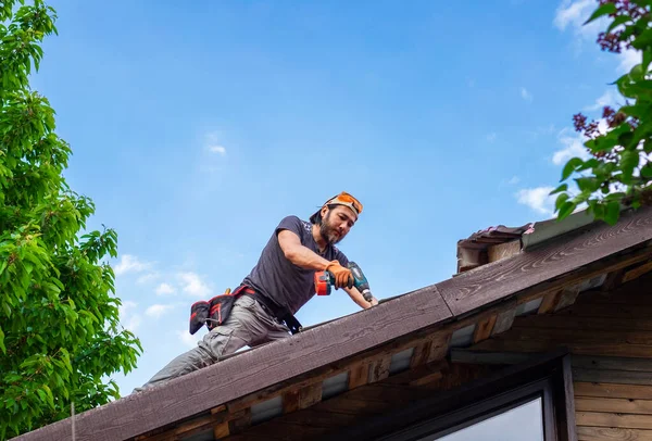 Homem trabalhando no telhado usando chave de fenda elétrica — Fotografia de Stock