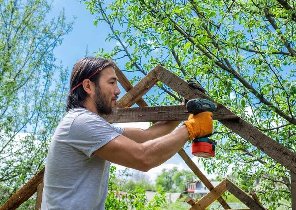 Человек делает деревянную крышу с помощью электрической отвертки — стоковое фото