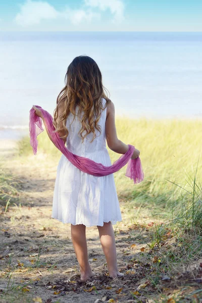 Holčička na pláži s růžovou šálu — Stock fotografie