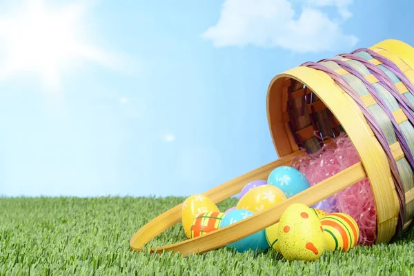 Spilled basket of easter eggs in grass — Stock Photo, Image