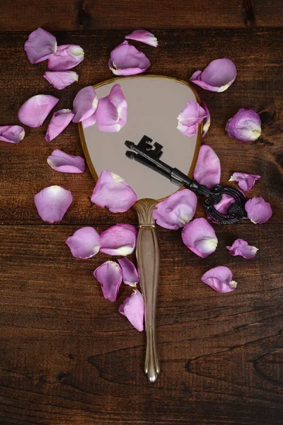 Mirror with key and rose petals — Stock Photo, Image