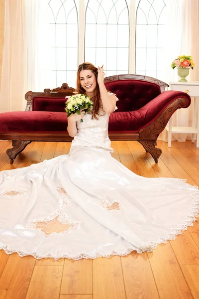Смеющаяся невеста сидит на полу — стоковое фото