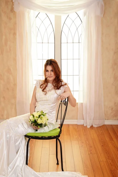 Retrato de novia sentada en una silla de metal por ventana —  Fotos de Stock