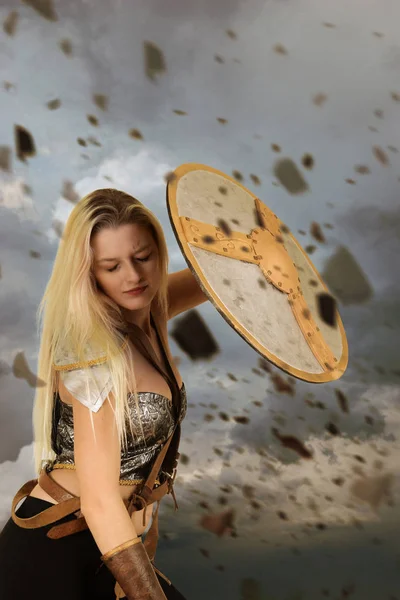 Mulher guerreira usando escudo para bloquear rochas voadoras — Fotografia de Stock