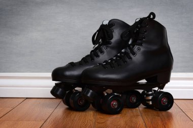 men's quad roller skates on wood floor clipart