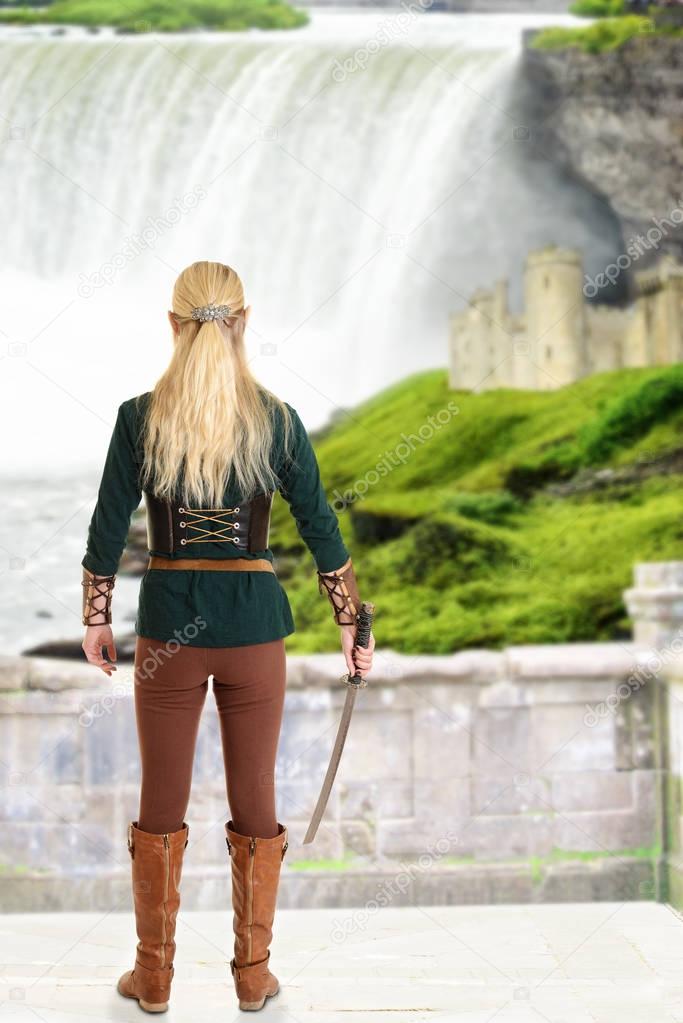 female elf with sword looking at waterfall