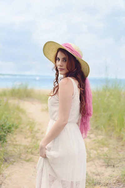 Roodharige vrouw met hoed op strand pad — Stockfoto