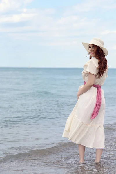 Винтажная рыжая женщина в шляпе у океана — стоковое фото