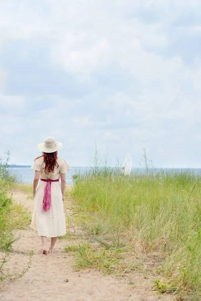 Donna con cappello che cammina sul sentiero della spiaggia — Foto Stock