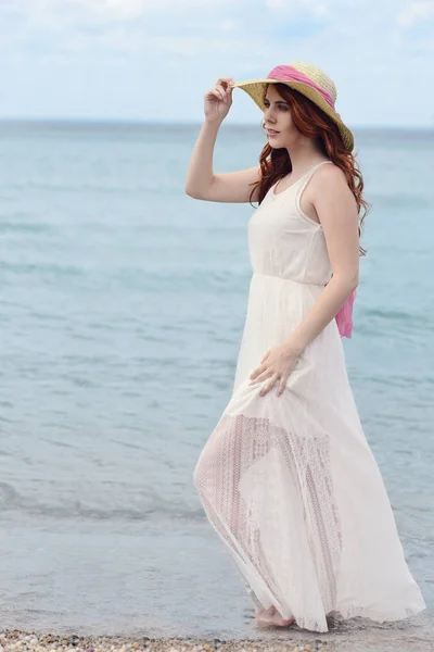 Femme marchant dans l'eau à la plage portant une robe blanche — Photo