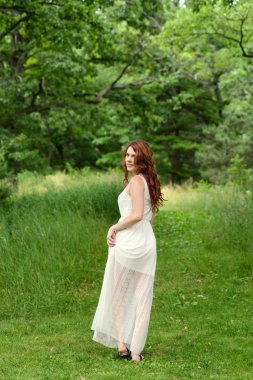 orman yolu üzerinde yürüyen Kızıl saçlı kadın