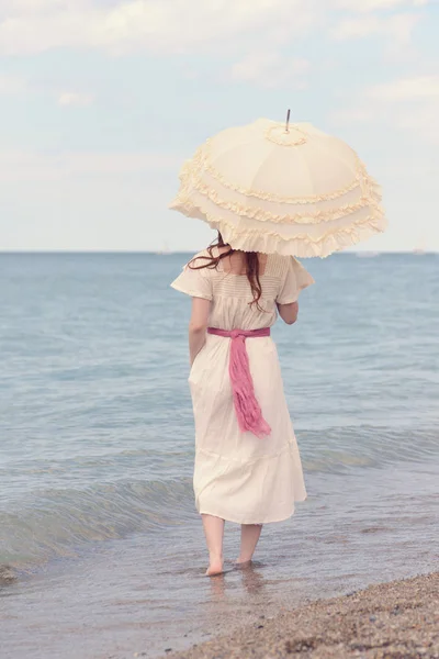 Mulher vintage na praia com guarda-sol — Fotografia de Stock